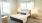 Furnished and carpeted bedroom with large windows inside apartment homes at The Rivi